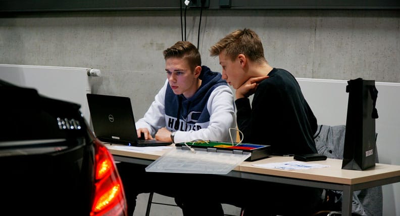 Zwei Schüler arbeiten an einem Computer in einer Montagehalle.