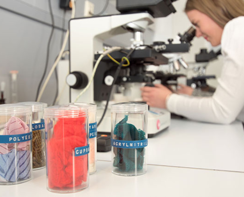 Eine Mitarbeiterin im Forschungsinstitut untersucht Polyesterfasern.