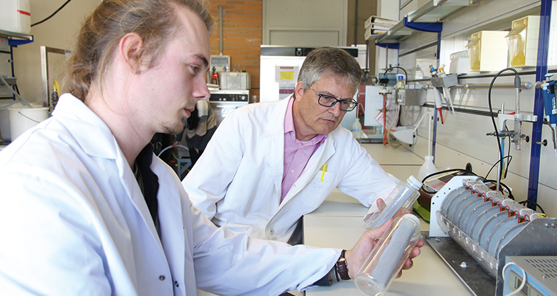 Alexander Behr (links) und Prof. Markus Röhricht begutachten im Labor zwei Kunststoffflaschen, mit denen verschmutztes Wasser desinfiziert werden kann.